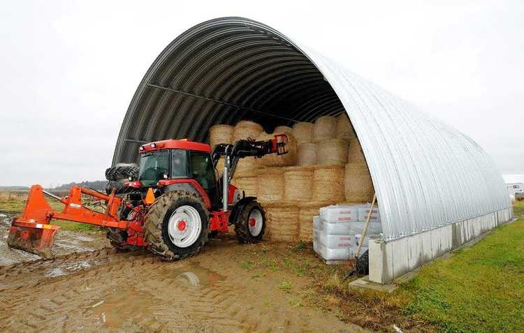 Traktor kör in höbalar i en hall